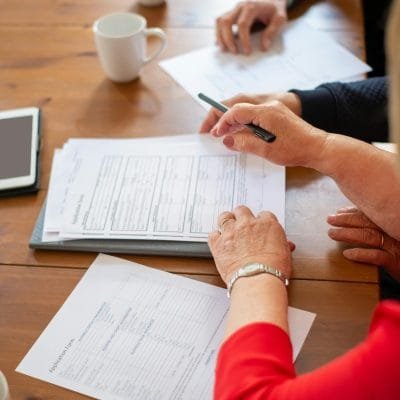 Business professionals reviewing contracts at a table, accompanied by coffee and a digital tablet.