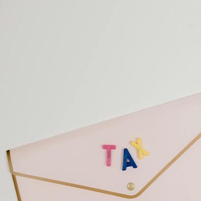 Pink envelope with TAX letters arranged on top, symbolizing tax-related themes.