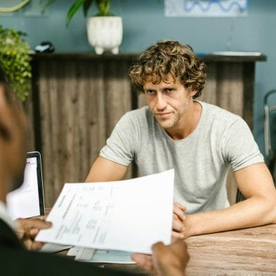 Two men in discussion over documents during a business meeting in a contemporary office setting.
