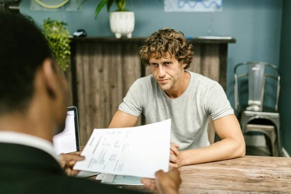Two men in discussion over documents during a business meeting in a contemporary office setting.